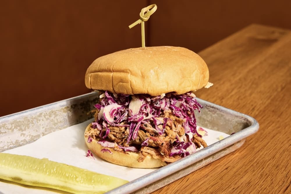 a tray with a burger and pickle spear