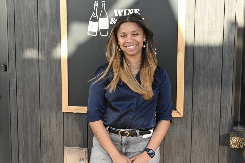 a girl wearing a blue shirt and jeans in front of a black wall