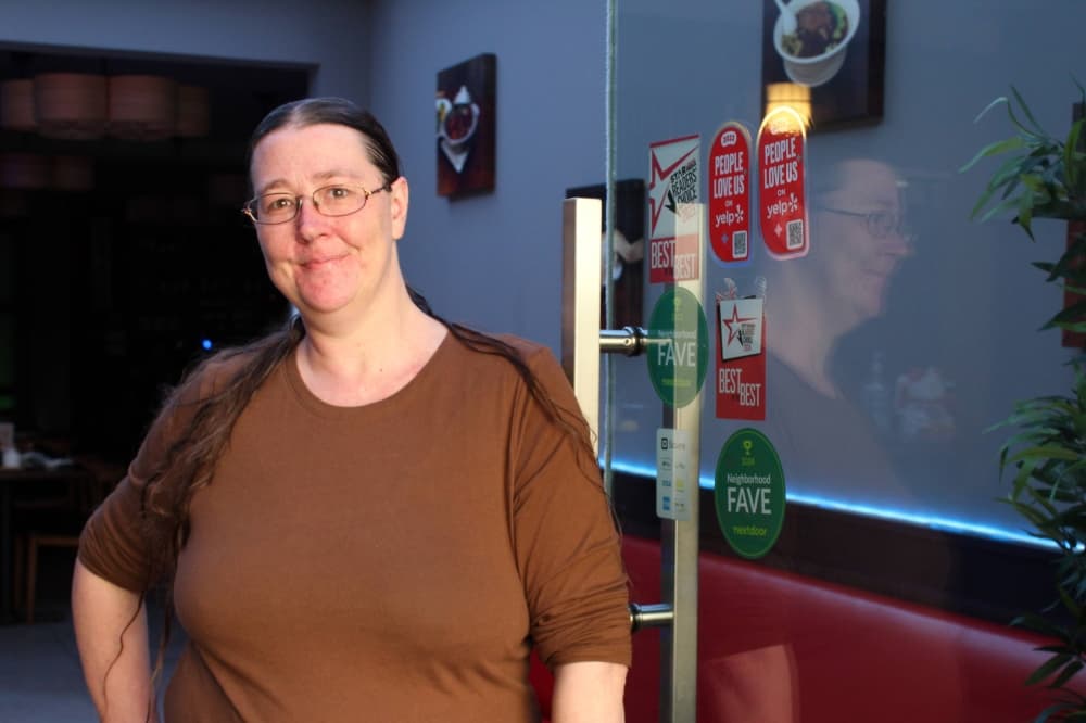 Female standing next to a door leading to a restaurant. 