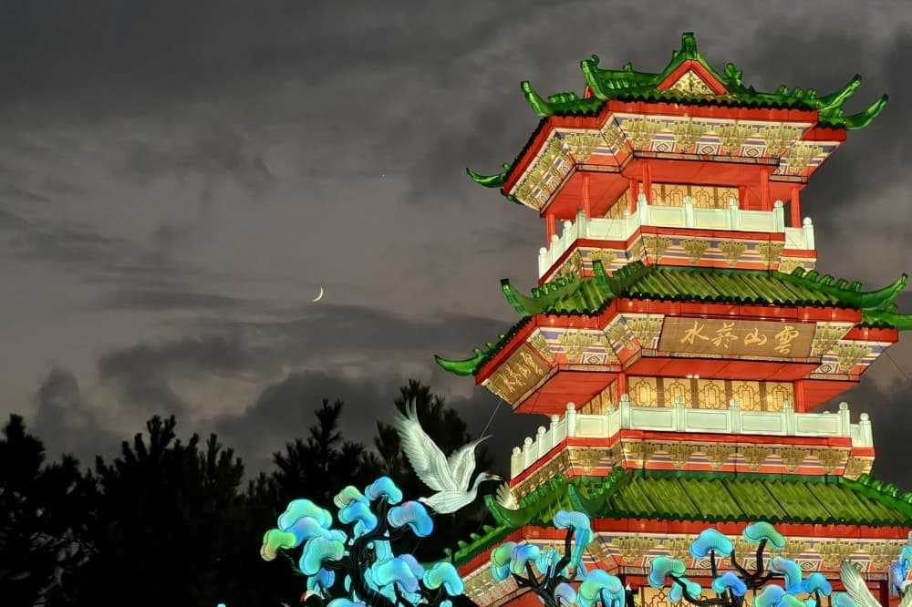 the top of a temple is lit up against a dark sky