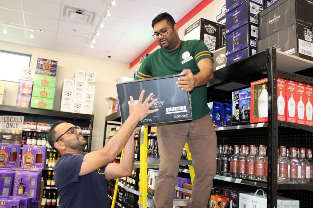 Pelican Liquor Owner Monty Patel (right) and a store employee stock shelves at the McKinney store, located at 1880 Bray Central Drive.