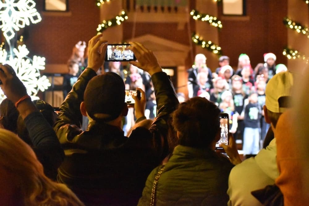 dad with an iphone recording a performance on a stage