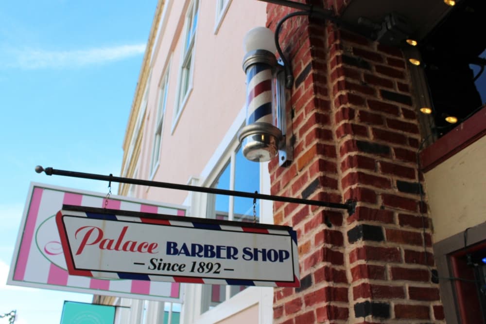 Exterior of a brick building with an attached sign reading Palace Barber Shop since 1892. 