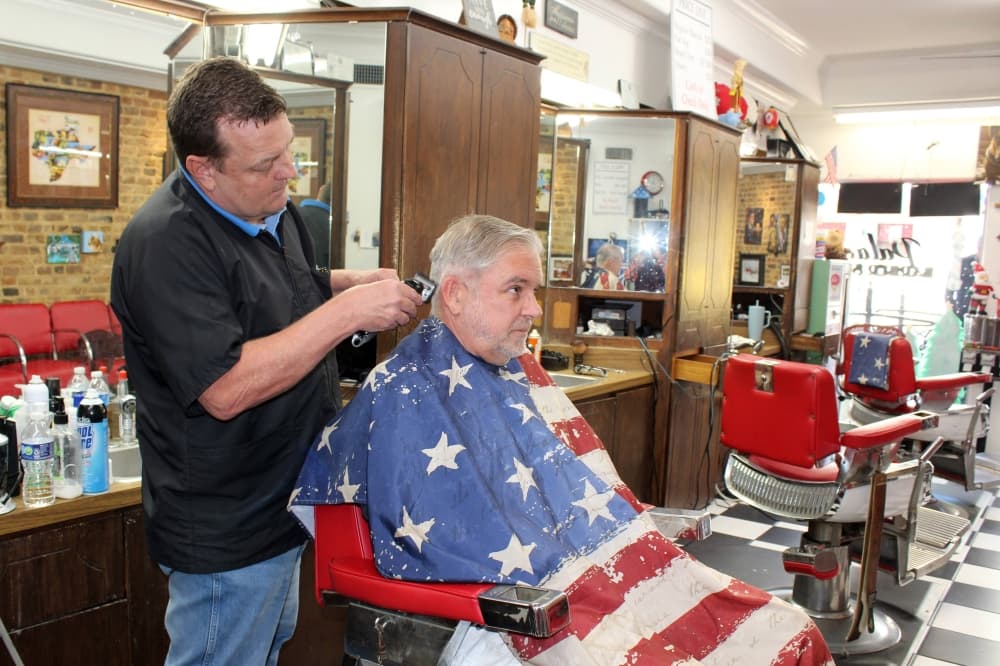 Male cutting a male's hair in a barber shop. 