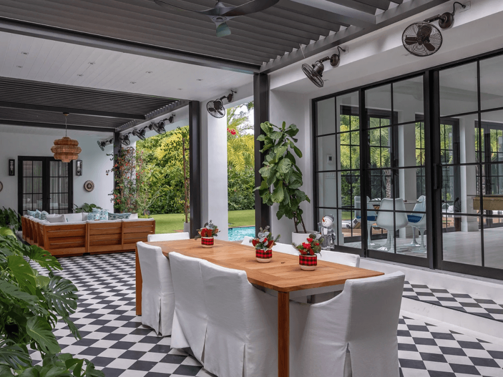 An open-air dining and lounge area featuring checkered flooring and modern black-framed windows