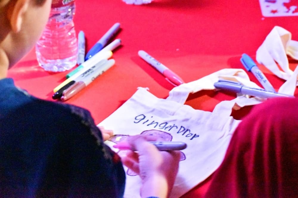 a person colors on a canvas tote bag
