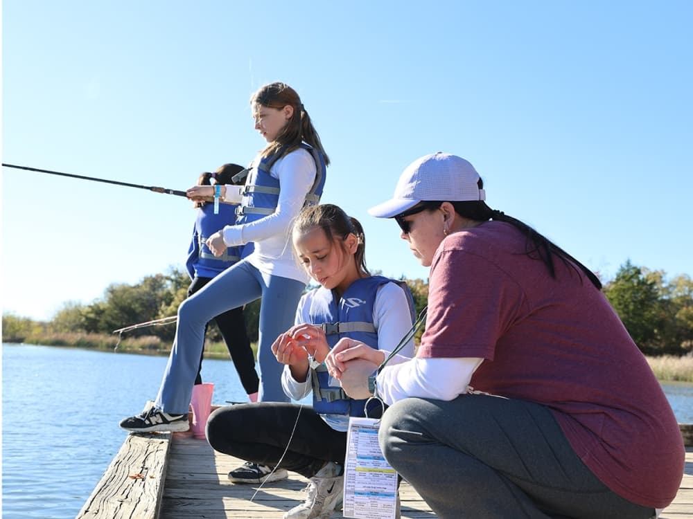 Students take part in a hands-on fishing activity during 5th Grade Camp, learning outdoor skills and exploring nature.