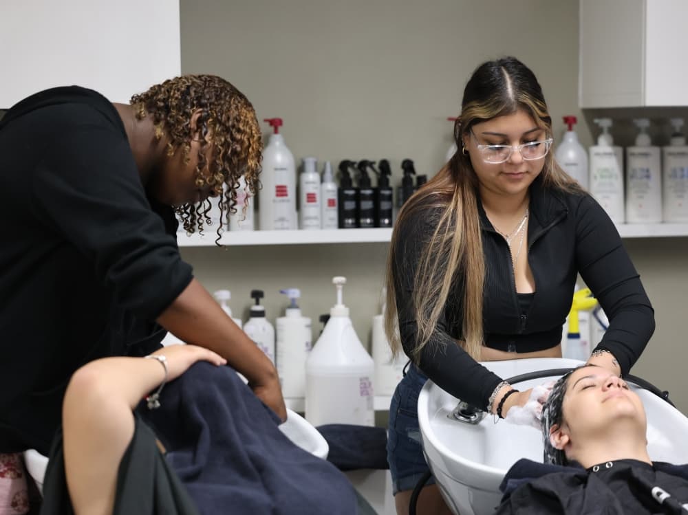 The hairdressing academy provides students with real-world cosmetology experience, including shampooing and client care skills.