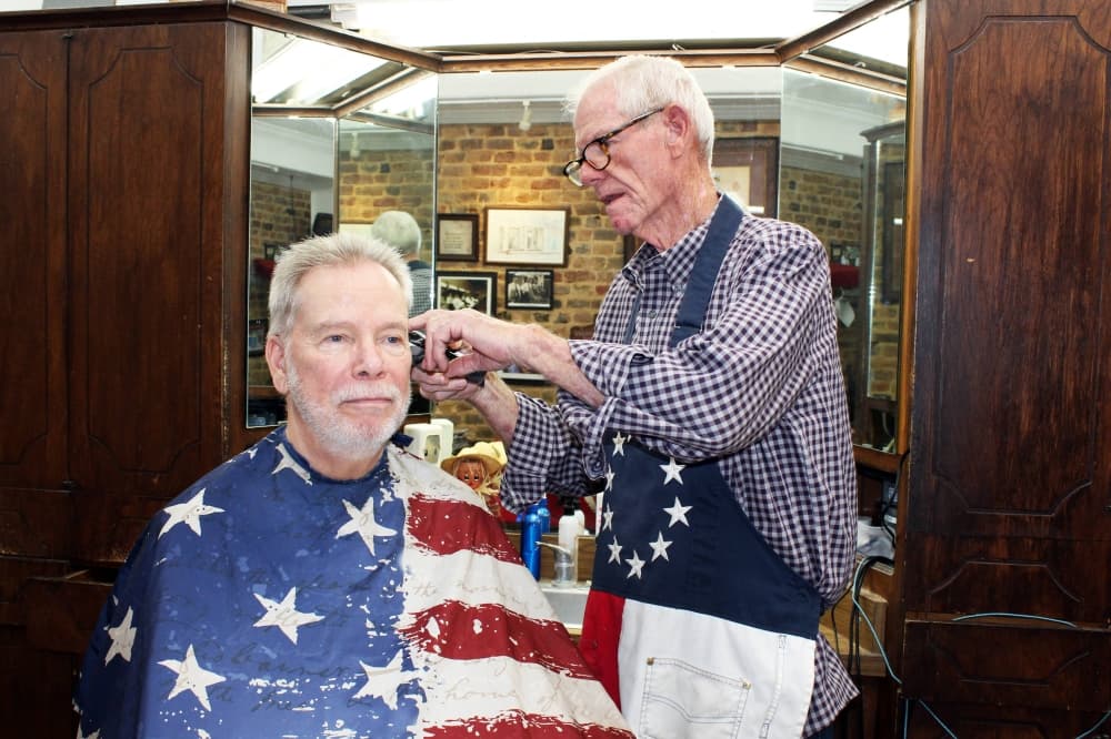 Male giving another male a haircut in a barber shop. 