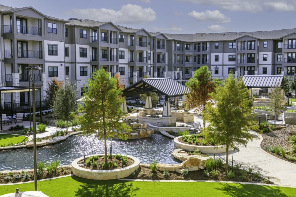 apartment complex with water and trees in front