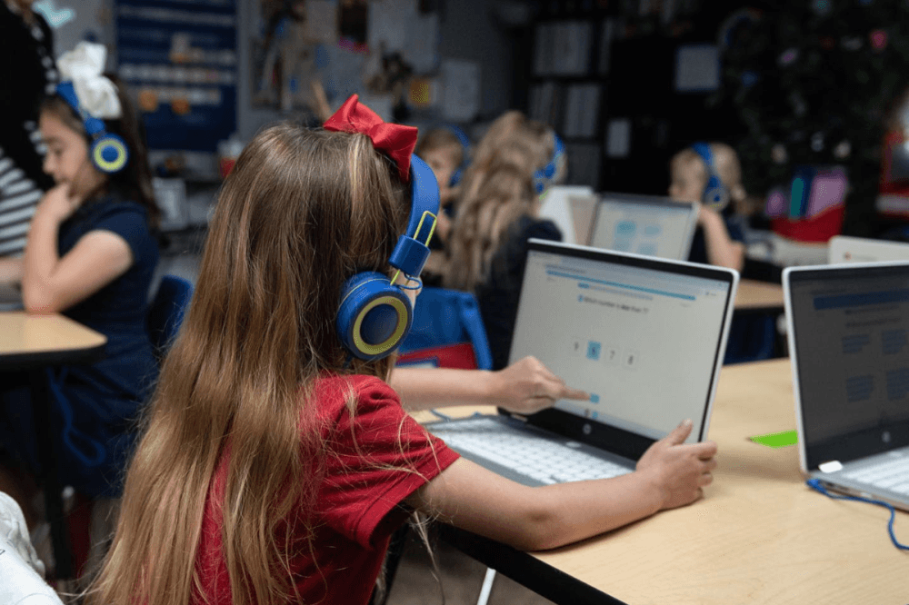 a young girl wearing headphones works on a tablet