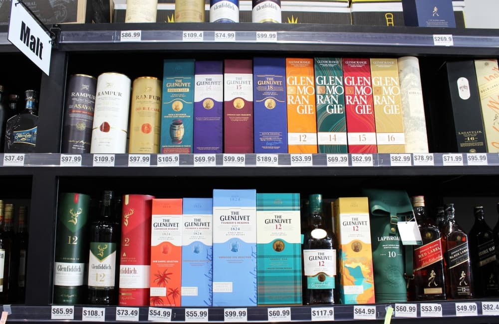 Shelves of alcohol with a Malt section sign affixed to a shelf. 