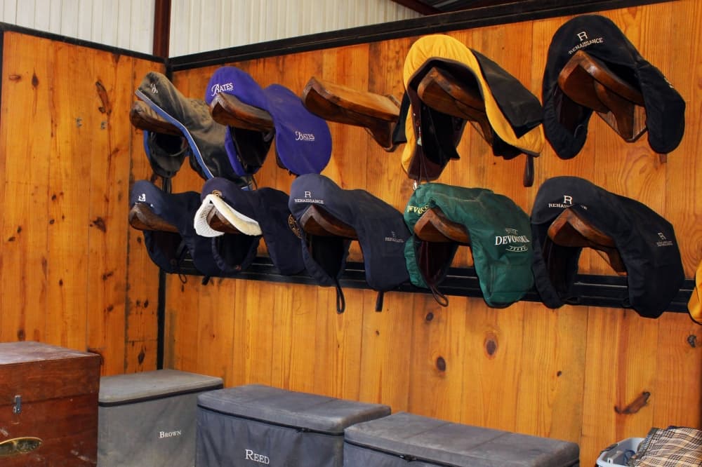 Saddles hanging on a wall in a stable. 