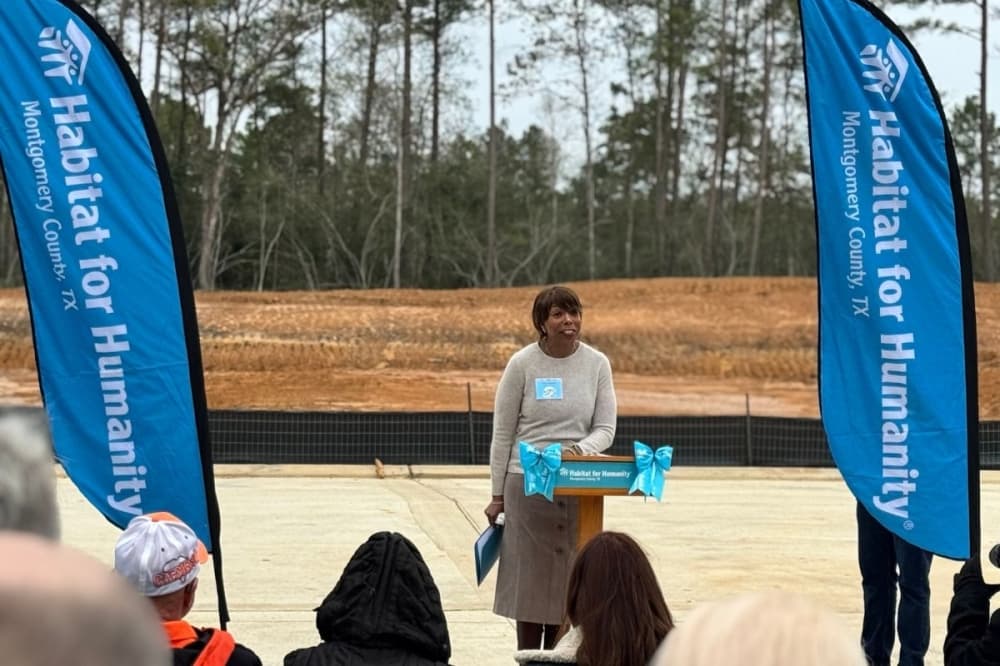 a woman stands between two blue flags