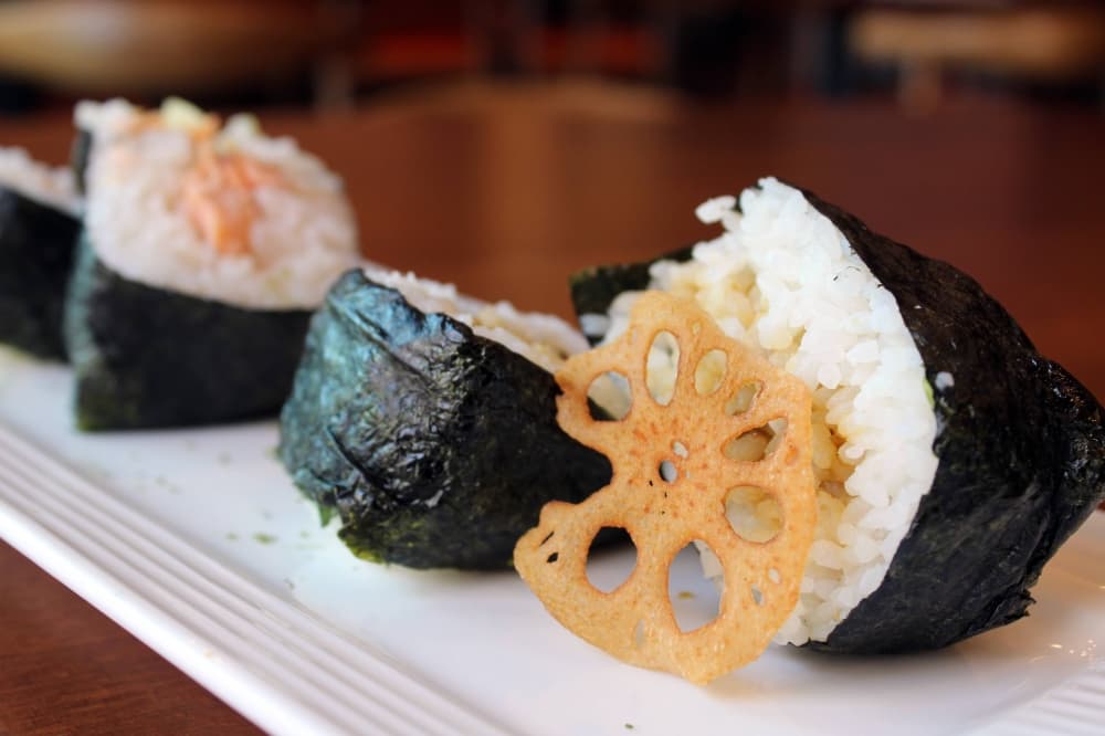 Rice balls cut in half  wrapped in seaweed and filled with a protein. 
