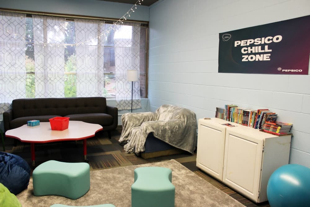 Room featuring a couch and soft chairs and a banner reading Pepsico Chill Zone.