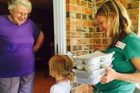 Vertalee stands in doorway looking at a adult and child volunteer