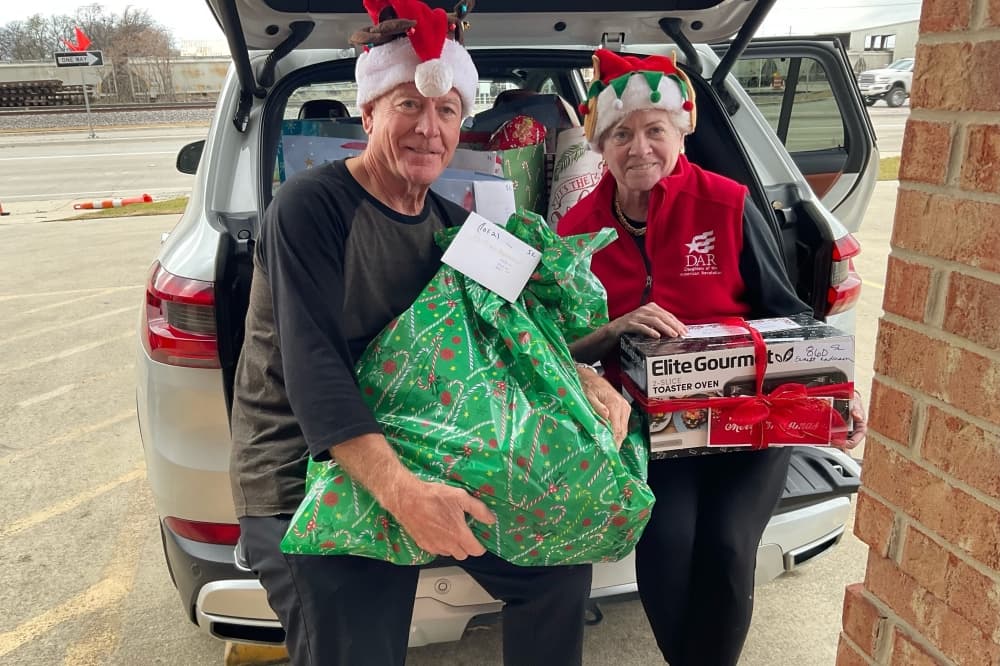 Volunteers pose with gifts outside their car
