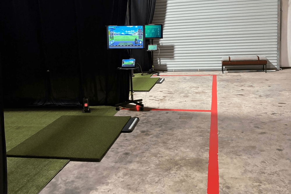 Inside view of The Practice Lab showing individual indoor golf bays with virtual driving ranges