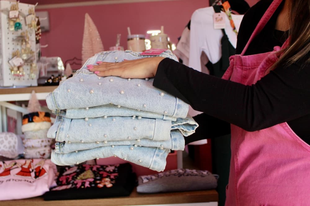a woman hold a stack of folded blue jeans