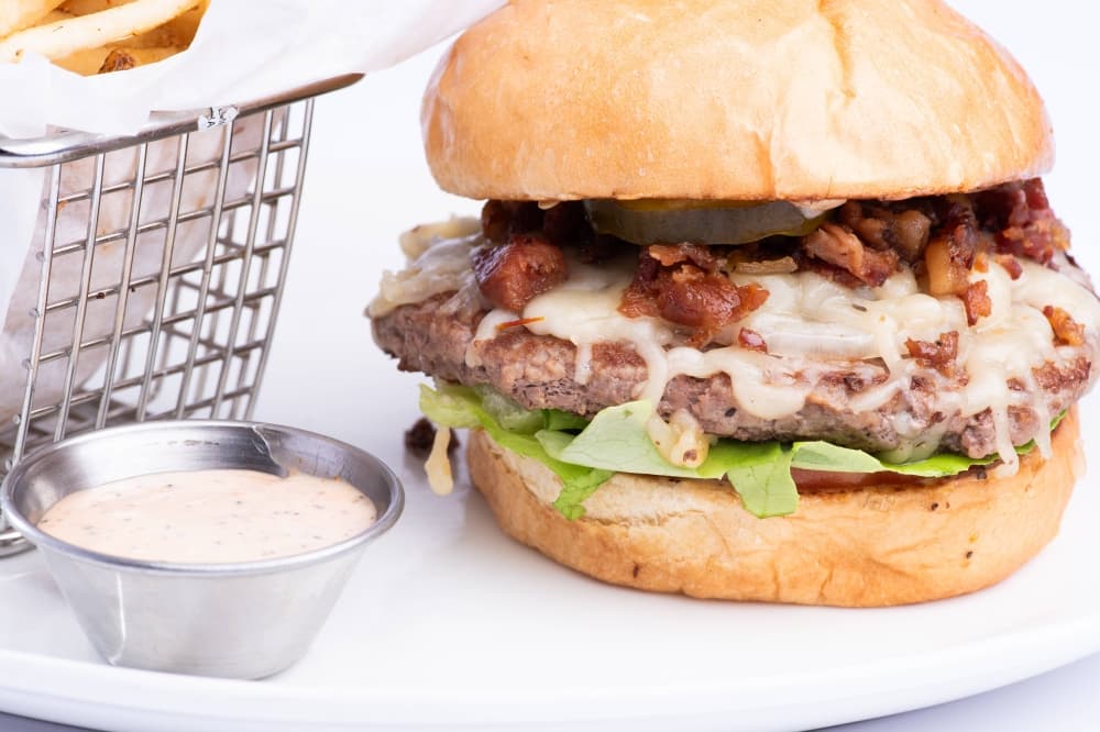Burger topped with bacon and sauce on a bun. 