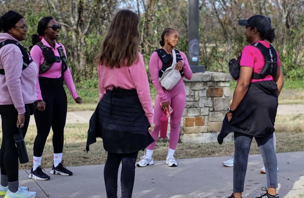 A group of women in athletic wear standing in a circle outside