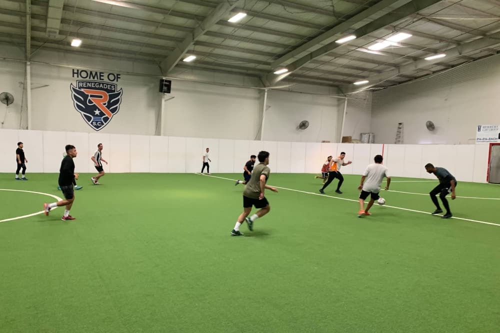 Men playing soccer on an indoor field. 