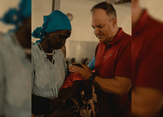 Preacher prays over baby on mission trip