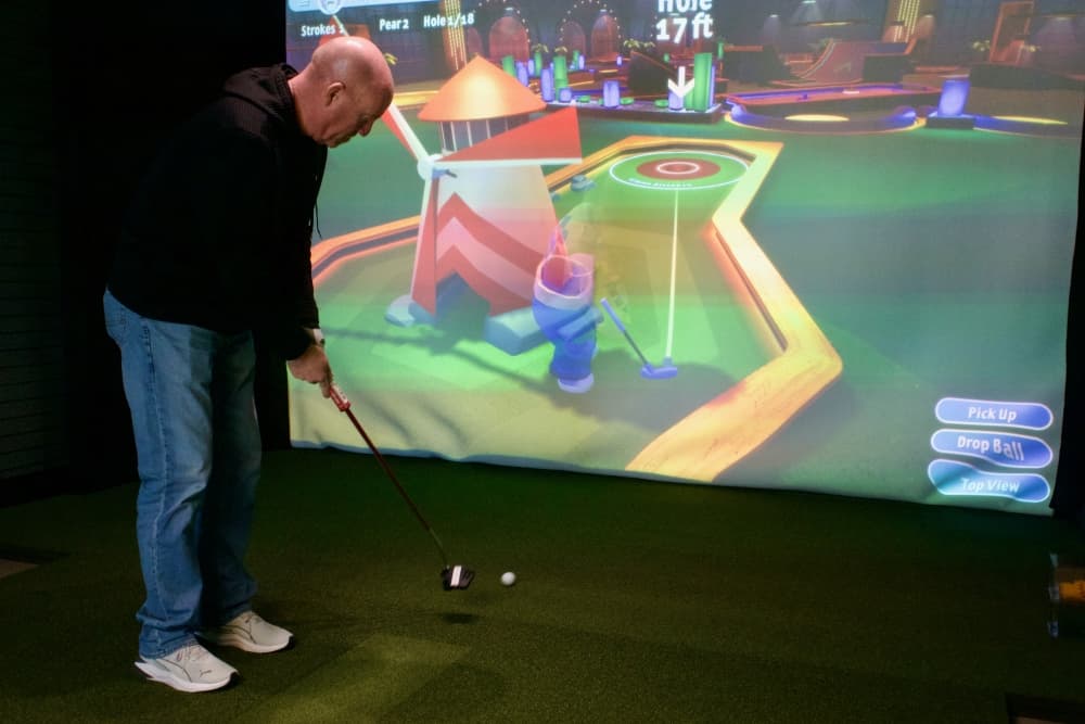 Owner Tommy Hunter plays miniature golf at Precision Golf Lab. (Adam Doe/Community Impact)