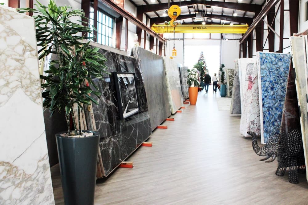 An aisle in a warehouse filled with stone slabs on either side. 