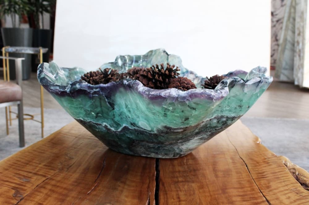 A bowl made of varying shades of stone sitting on a wooden table. 