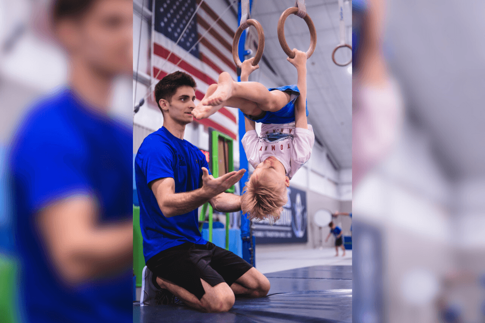 Coach spotting gymnast on rings