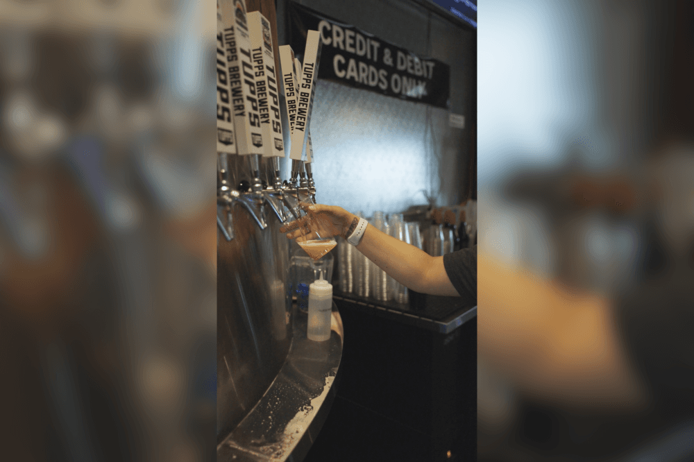 Person filling glass with beer on tap