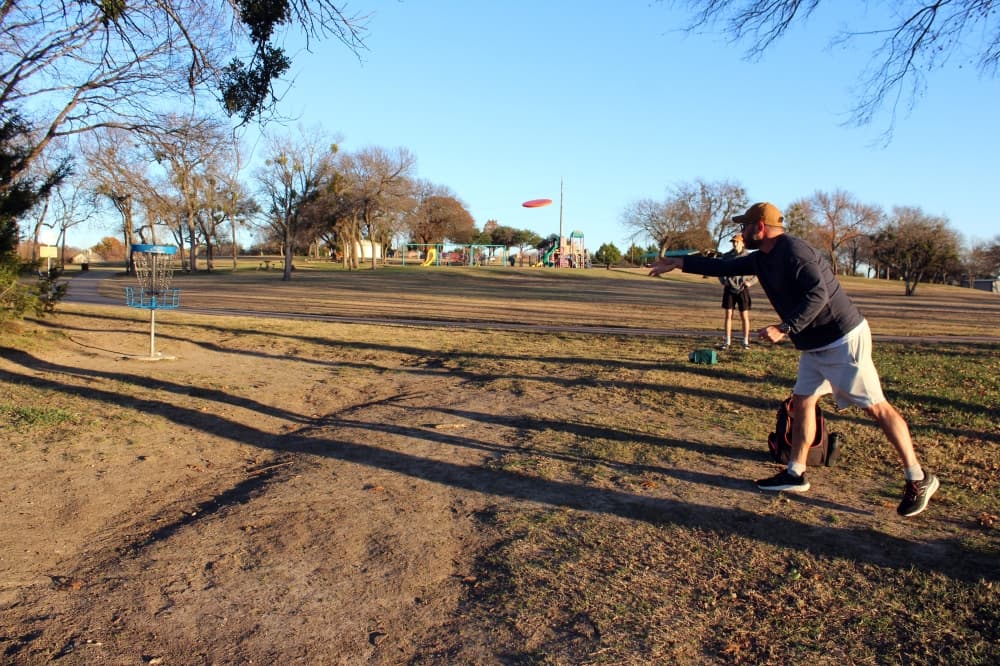 Sam and Wyatt Roman play disc golf at Richardson's Breckinridge Park. (Karen Chaney/Community Impact)