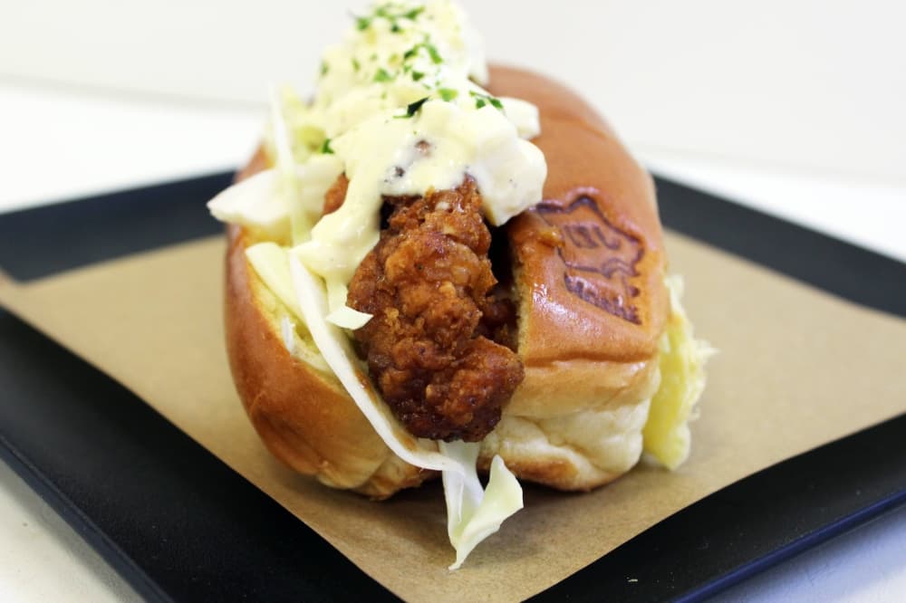 Fried chicken tender on a bun featuring Hoshi branding and topped with an egg sauce. 