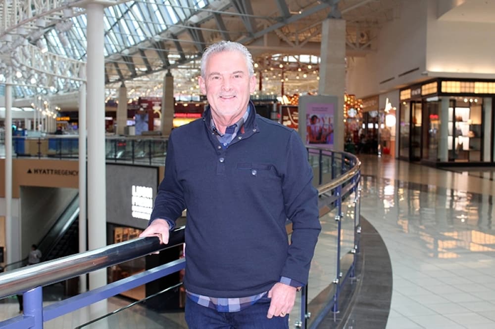 Male leaning against a rail in a mall. 