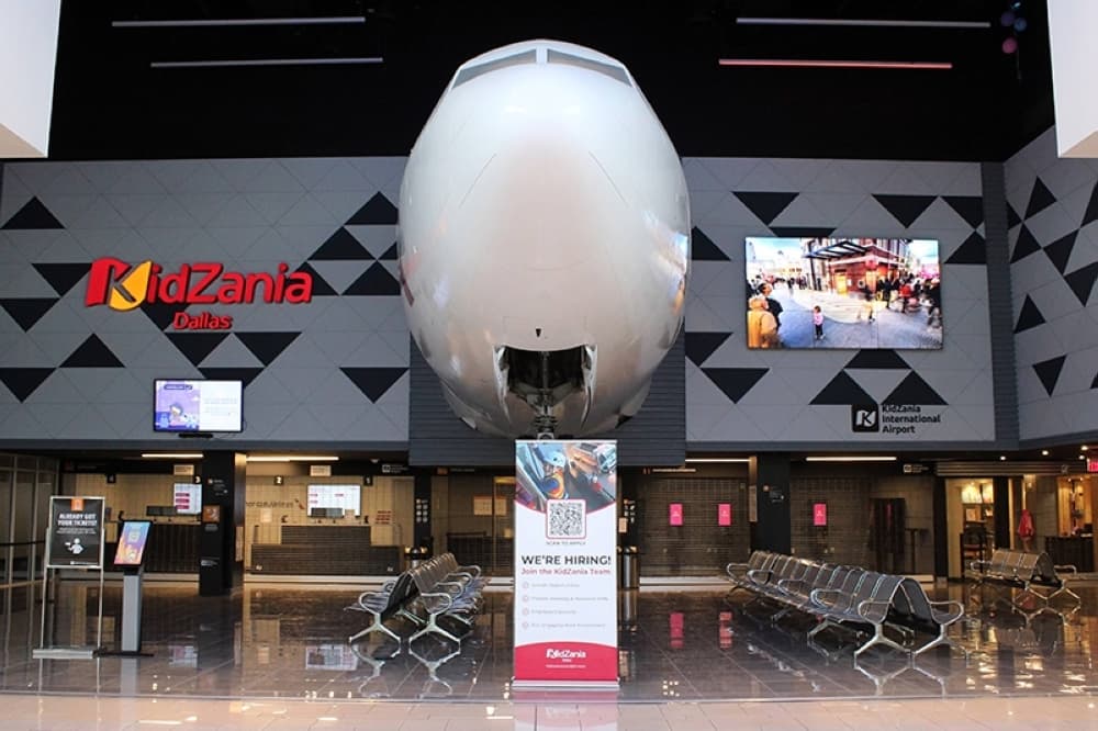 Exterior of a business featuring the nose of an airplane and KidZone signage. 