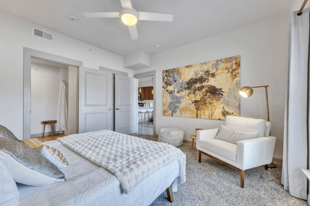 Bright primary bedroom inside a Waters at Sunrise luxury apartment with large windows, neutral finishes, and space for a full bedroom furniture set