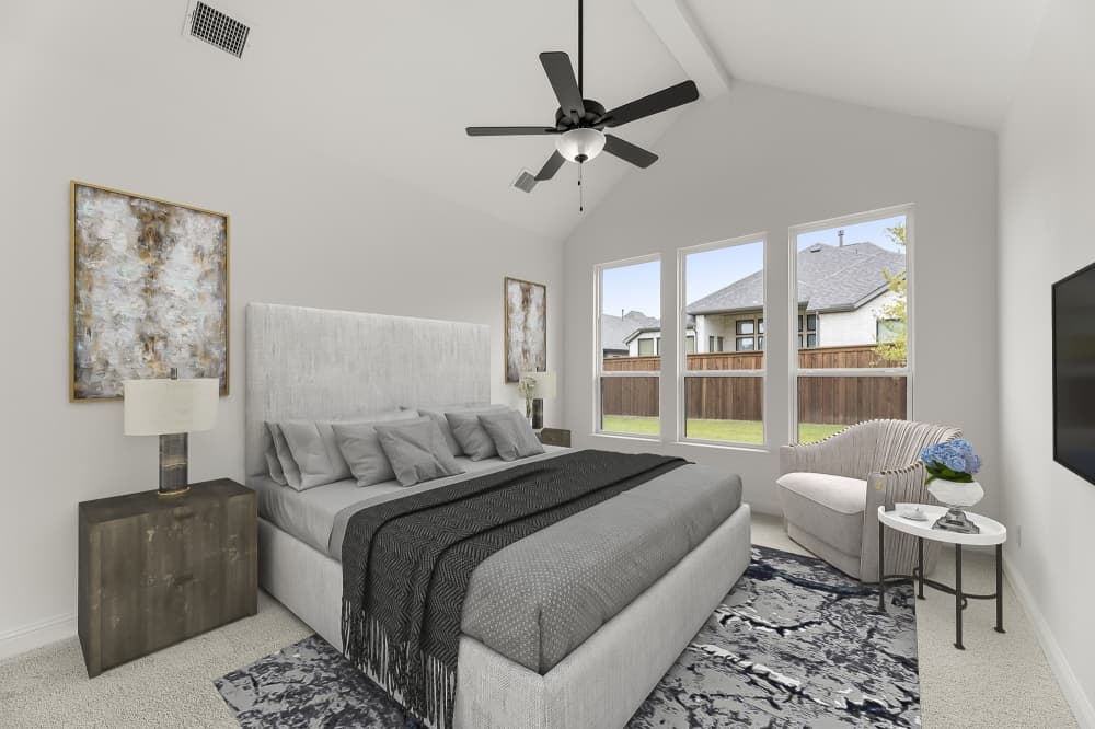 Primary bedroom suite in Drees Custom Homes Bastrop collection with large windows and designer finishes