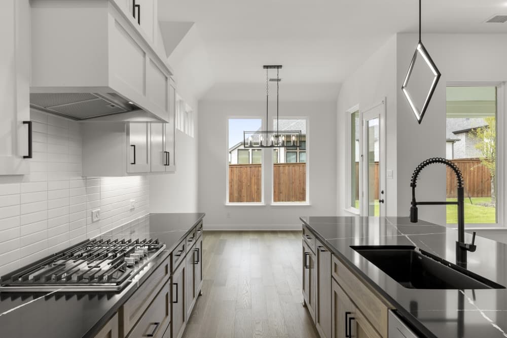 Modern open concept kitchen in Drees Custom Homes New Colony Bastrop with quartz countertops and stainless steel appliances