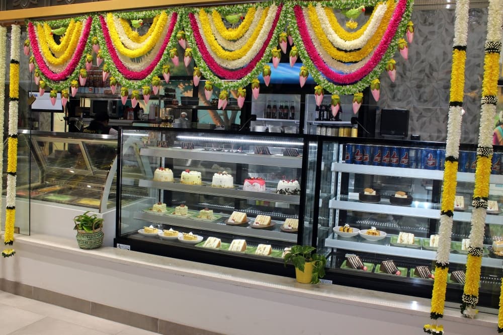 The front of bakery cases filled with baked goods with festive yellow and red banners and streamer decorations. 