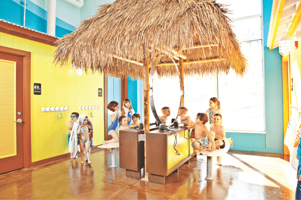 Swim instructor teaching young child beginner swim lessons and water safety techniques at Goldfish Swim School for kids