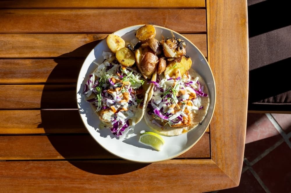 The fish tacos ($17) are blackened pollock, with cabbage slaw, poblano lime crema, chipotle crema fresca, lime and cilantro. (Ethan Thomas/Community Impact)