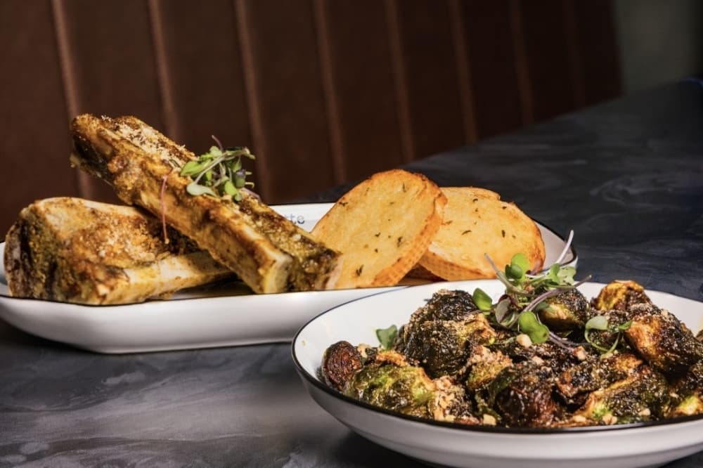 Featured is the the bone marrow which includes roasted bone marrow, parsley butter, panko, chives and garlic toast; and the brussel sprouts truffle honey and roasted almonds. (Courtesy Petite Suzette)