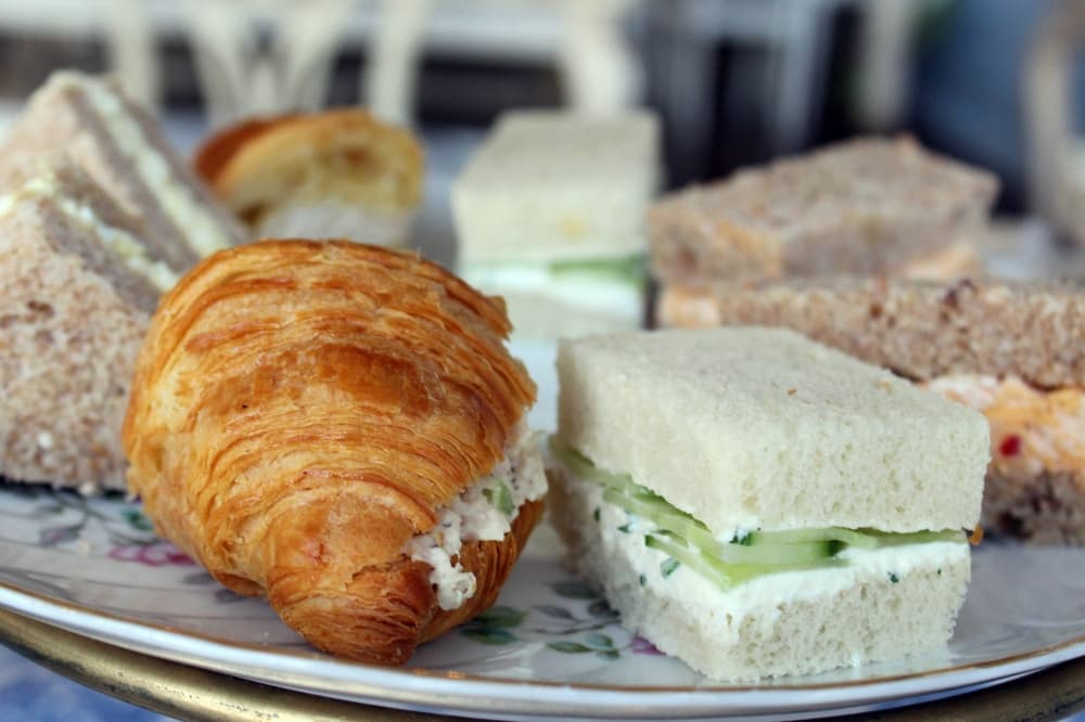 One croissant sandwich with chicken salad filling, one white crustless bread sandwich with cucumber filling. 