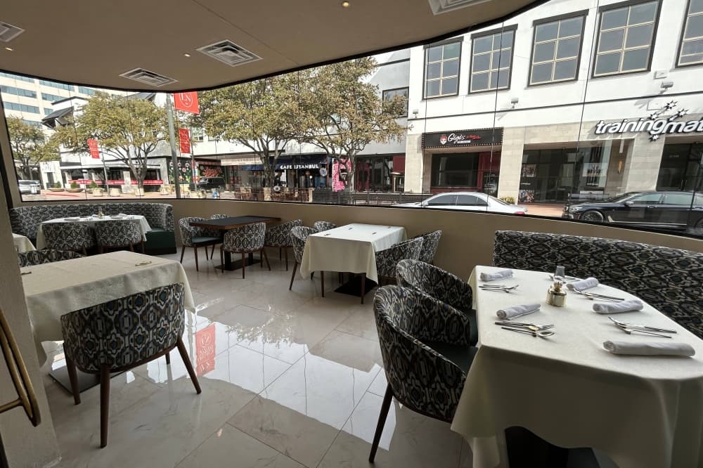 Enclosed patio at a restaurant with a view of an outside mall and cars on a street. 