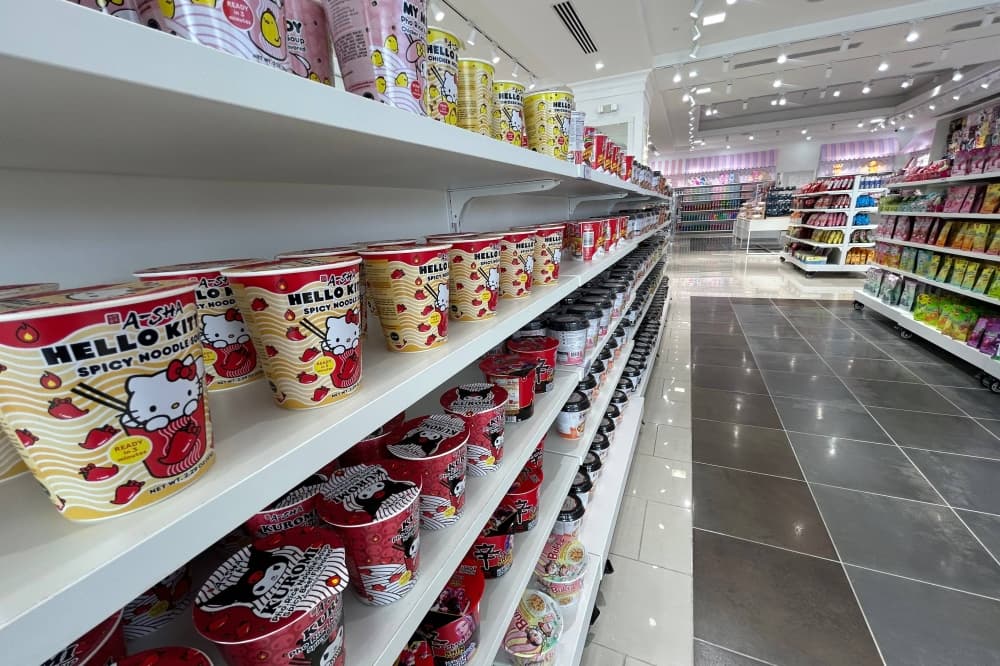 Containers of ramen featuring Hello Kitty lined up on shelves in a store. 