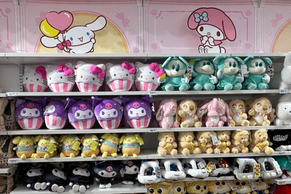 A variety of stuffed animals displayed on shelves in a store. 