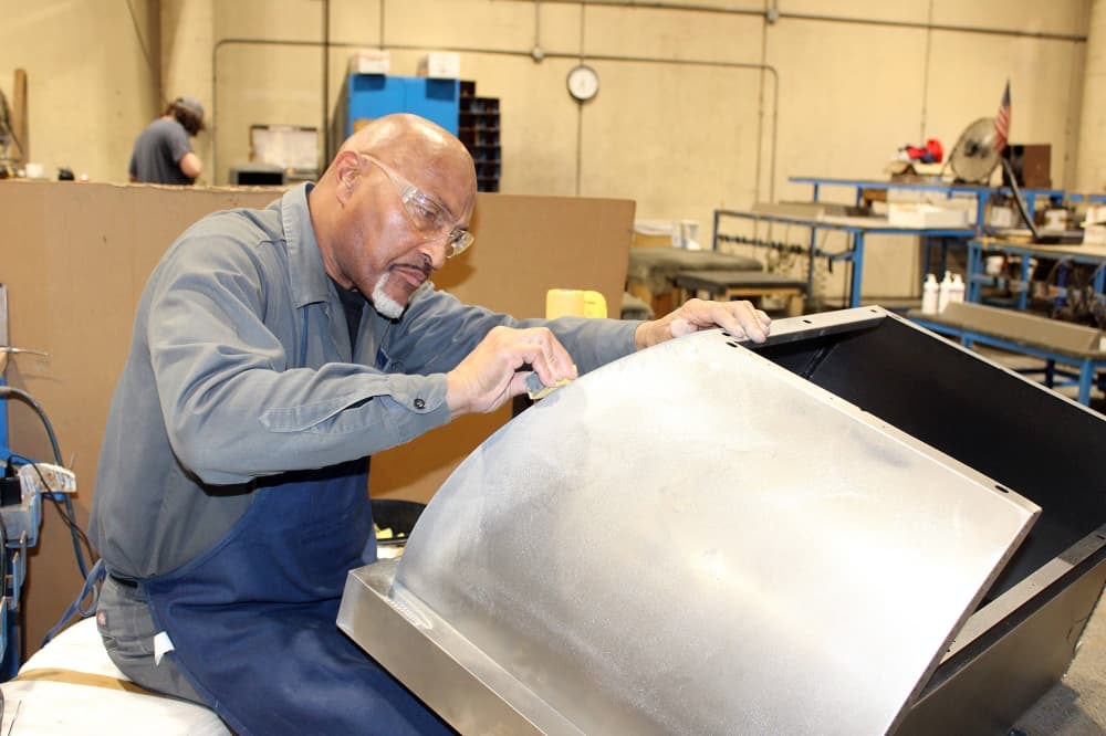 Male sanding a metal structure. 