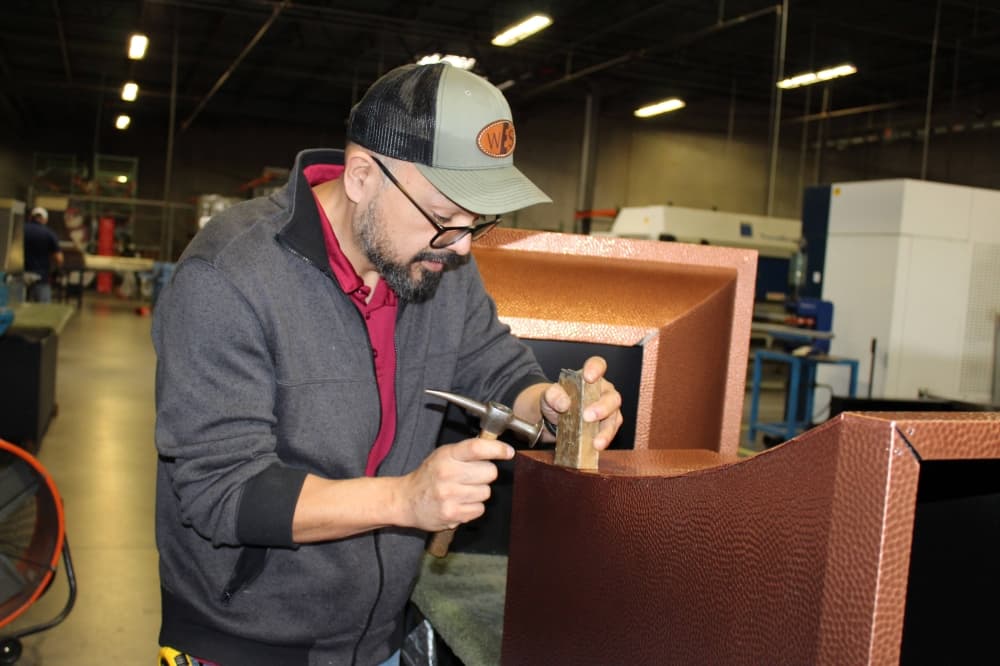 Male attaching copper overlay to a metal structure. 